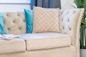 A beige tufted sofa with a cushion, a teal pillow, and a diamond-patterned pillow. - Stylish Three Bedroom House - Harborne - Parking - Garden (Harborne)