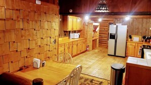 Un interior rústico de madera con comedor, cocina y una alfombra estampada.