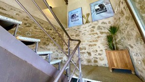 Una escalera con barandillas de metal, un muro de piedra y un banco de madera.