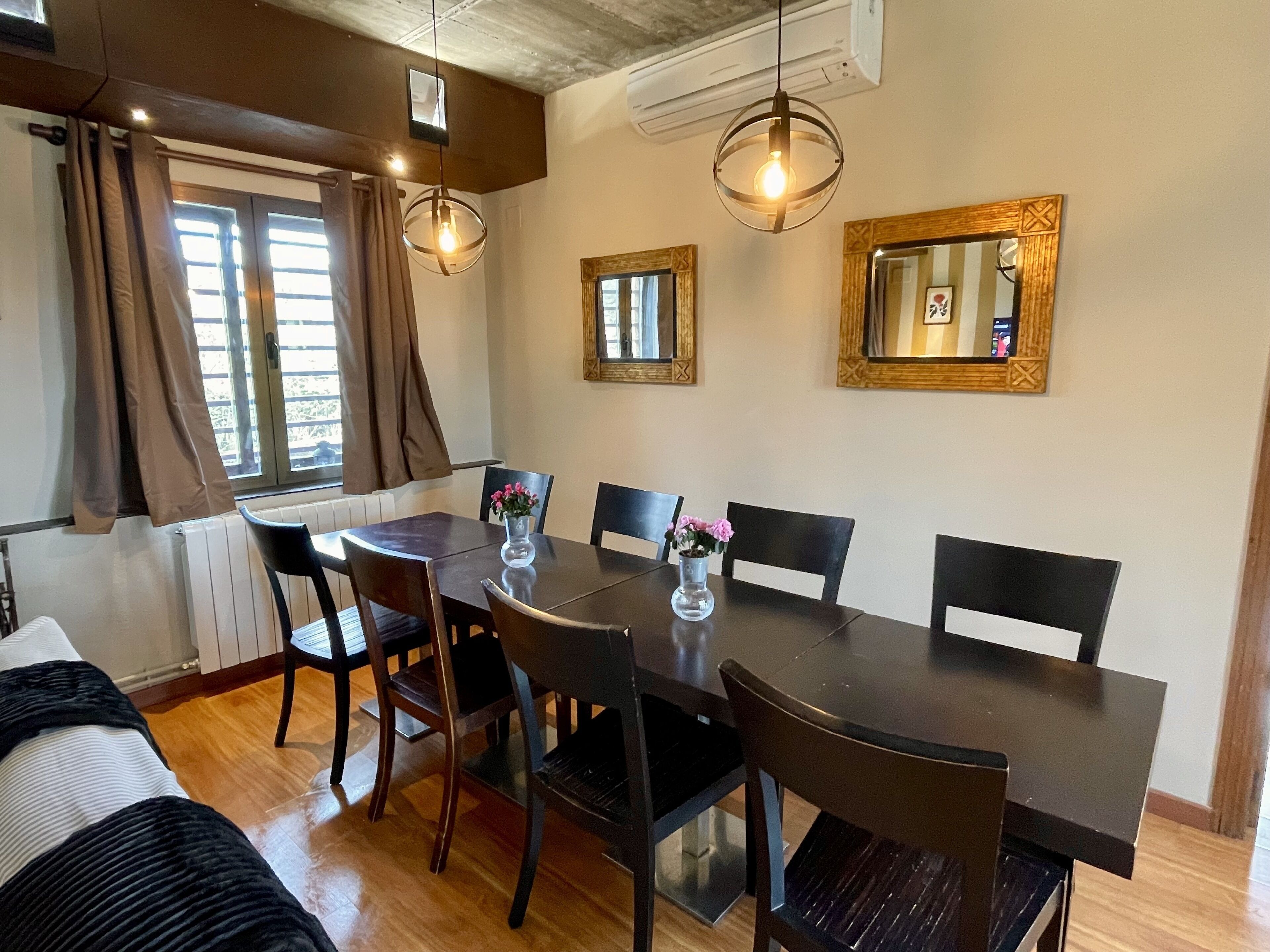 Un comedor con una mesa de madera oscura, seis sillas y dos lámparas colgantes.