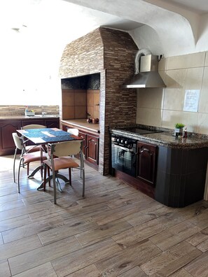 A kitchen with a built-in oven, a dining table with chairs, and a stone backsplash.