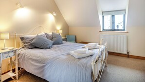 A bedroom with a bed, bedside tables, a window, and a radiator. - A lovely property in the perfect location, and it has parking too. (Wells-next-the-Sea)