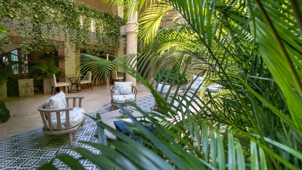 An indoor garden with seating areas, a central column, and lush greenery.