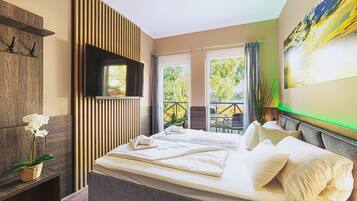 A bedroom with a bed, a TV mounted on the wall, and a balcony with outdoor furniture.