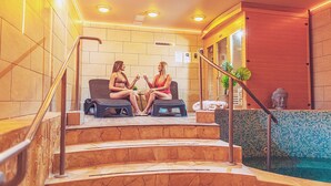 A spa area with two women sitting on wicker chairs, a small pool, and a Buddha statue. - Mártoni Resort & Restaurant (Szigetszentmarton)
