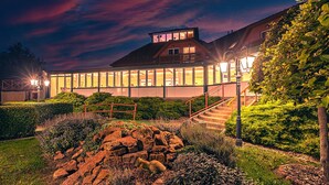 A modern house with a large glass extension, surrounded by well-maintained gardens and a stone pathway. - Mártoni Resort & Restaurant (Szigetszentmarton)