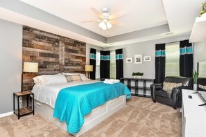A bedroom with a bed, a desk, a chair, a ceiling fan, and a wall with a wooden panel design.