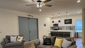 A modern living room with two sofas, a coffee table, and a ceiling fan. - Hidden Bungalow 1 1/2 blocks from the beach (Bay St. Louis)
