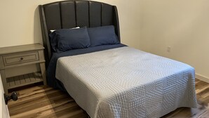 A bedroom with a bed, a nightstand, and a wooden floor. - Hidden Bungalow 1 1/2 blocks from the beach (Bay St. Louis)