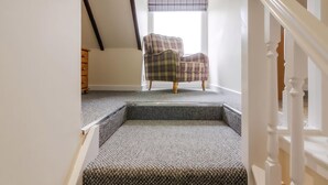 A staircase leading to a room with a plaid armchair and a wooden dresser. - Dalnaglar Cottage - UK30260 (Glenshee, Cairngorms)