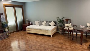 Un dormitorio con una cama de madera, una mesita de noche, una silla, una mesa y una planta en maceta.