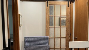 Una habitación con piso de madera, puerta corredera de vidrio y ventana de estructura metálica.