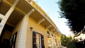 Un edificio con balcón, una puerta y una ventana con contraventanas.