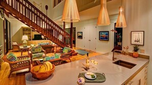 A spacious kitchen with a large island, wooden furniture, and pendant lighting. - B.I. Kaiakea,  Sleeps 12, Hot Tub, Astounding Oceanfront in Tranquil Puako! (Kamuela)