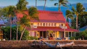 A two-story house with a red roof, surrounded by palm trees and a beach. - B.I. Kaiakea,  Sleeps 12, Hot Tub, Astounding Oceanfront in Tranquil Puako! (Kamuela)