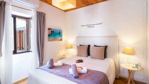 Une chambre d’hôtel avec un lit, deux lampes de chevet, un tableau, une citation affichée sur le mur et un appareil de climatisation.