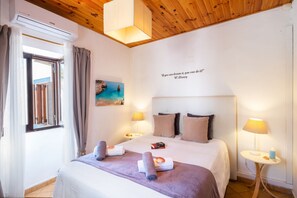 Una camera d'albergo con un letto, due lampade da comodino, un quadro, una citazione sulla parete e un condizionatore d'aria.