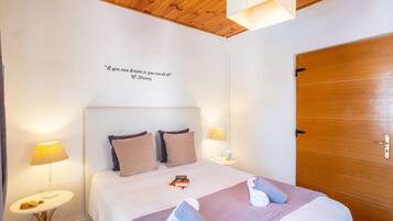 Une chambre d’hôtel avec un plafond en bois, un lit doté d’une tête de lit, deux lampes de chevet, une porte et une citation inspirante sur le mur.