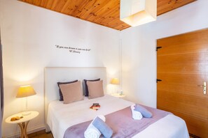 Ein Hotelzimmer mit Holzboden, einem Bett mit Kopfteil, zwei Nachttischlampen, einer Tür und einem motivierenden Zitat an der Wand.