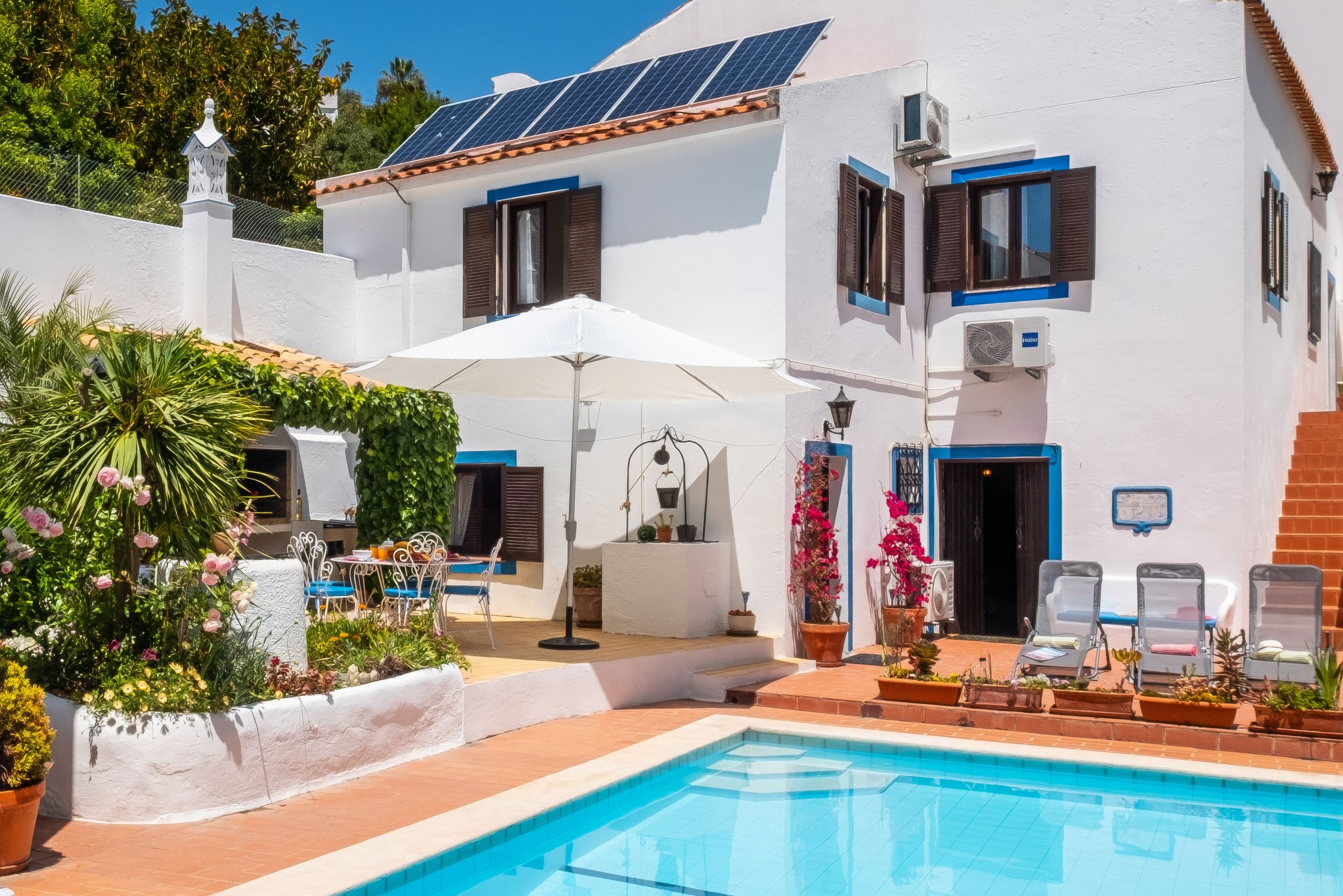 A poolside area with a pool, lounge chairs, and a dining setup with a table and chairs.