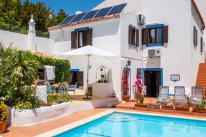 A poolside area with a pool, lounge chairs, and a dining setup with a table and chairs. - Villa w/ heatable pool & BBQ in Carvoeiro (Carvoeiro)