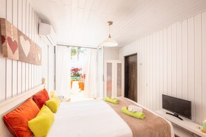 A hotel room with a bed, a TV, and a view of the outside.