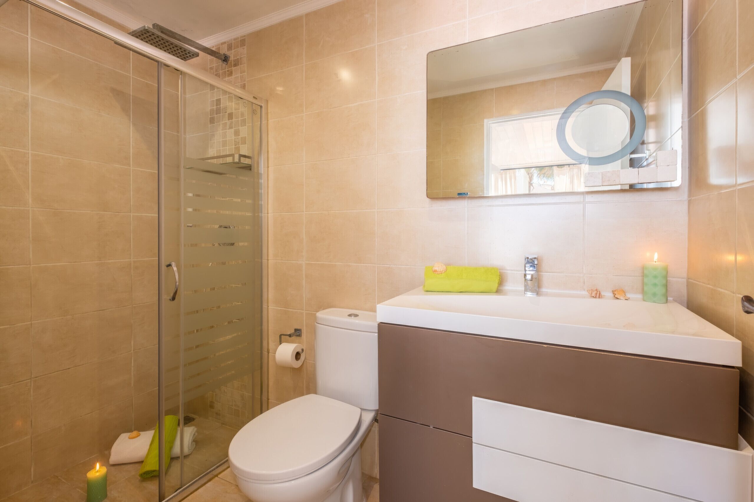 Une salle de bain avec une douche à parois de verre, des toilettes, un lavabo avec un miroir et un porte-serviettes.