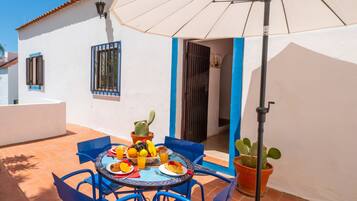 A patio with a table set for breakfast, including fruits and a cactus plant.
