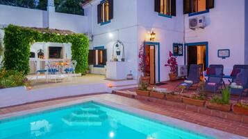 A poolside area with a pool, outdoor seating, and a covered patio.