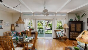 A dining area with wicker chairs, a glass table, and a ceiling fan. - B.I. Plumeria Cottage -Summer Rates! Perfect Couples Getaway in Magical Puako (Kamuela)