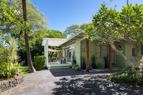 A house with a porch, a covered outdoor seating area, and a gravel driveway.