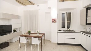 A compact living space with a kitchenette, dining area, and a TV.