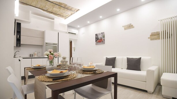 A modern living room with a dining area, white furniture, and a contemporary design.