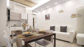 A modern living room with a dining area, white furniture, and a contemporary design.