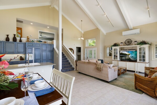 A spacious living area with a sofa, dining table, and a television. - Whale's Tail - 3BR Beachfront Home in Magical Puako! Steps to the ocean! (Kamuela)