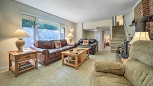 A cozy living room with a fireplace, leather sofas, and a staircase leading to another level.