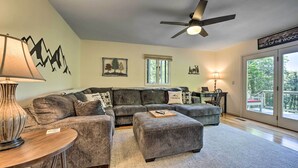 A living room with a sectional sofa, ottoman, lamp, and artwork on the walls.