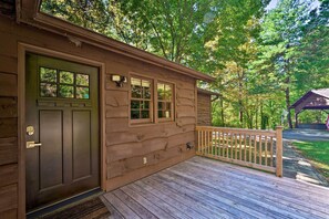 A wooden cabin with a front door, windows, and a deck.