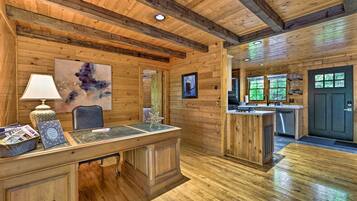 A wooden interior with a desk, chair, and artwork.