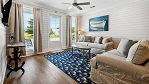 A modern living room with a sofa, a coffee table, and a TV mounted on the wall. - New 2 Bedroom Beach Rental in downtown Bay St Louis (Bay St. Louis)