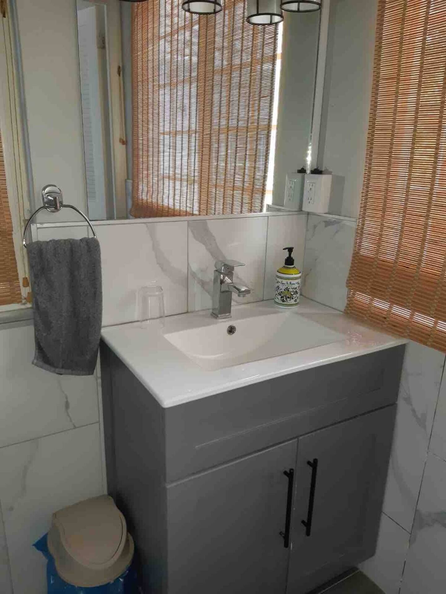 A bathroom with a white sink, a mirror, a towel rack, and a toilet.