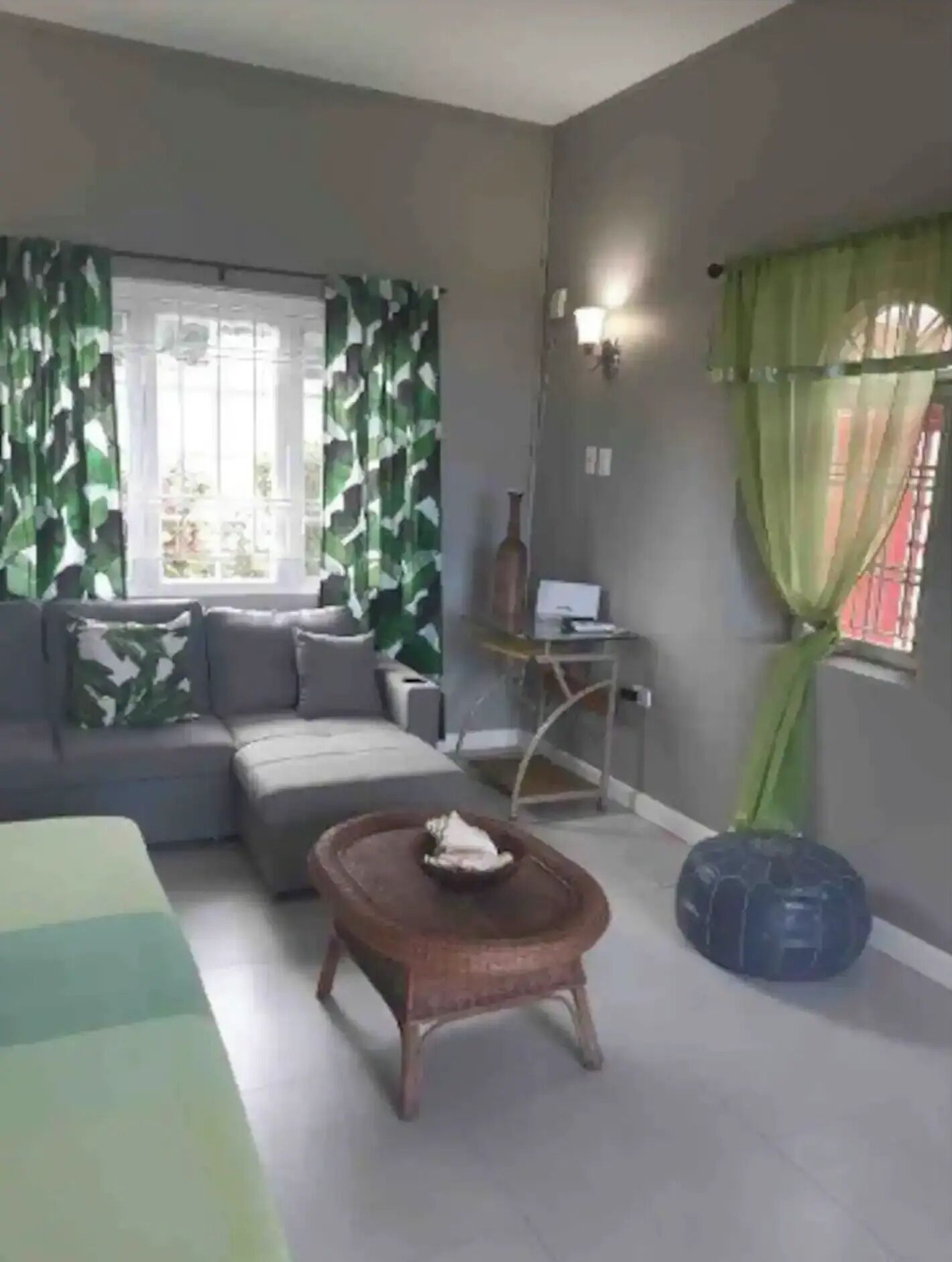 Una sala de estar con un sofá, una mesa de centro, una lámpara y una ventana con cortinas.