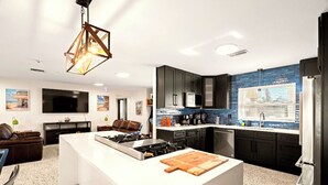 Une cuisine moderne dotée d’un îlot central, de meubles de couleur sombre et d’un revêtement mural en carreaux bleus.