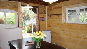 Ein Holzinterieur mit einem Tisch, einer Blumenvase, einem Pepsi-Schild und einem Fenster mit Blick auf Grünflächen.