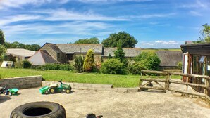 A rural farm setting with a green tractor, a large tire, and a wooden fence.