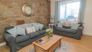 A living room with two grey sofas, a wooden coffee table, and a stone wall. - Redshank (Morpeth)