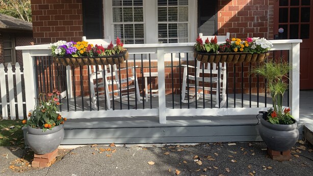A balcony with white railings, a black awning, and potted plants. - Cozy Cottage on Canton Street just steps away from nightlife, shopping and parks (Roswell)