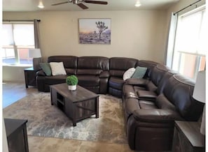 A living room with a sectional sofa, a coffee table, and a painting on the wall.