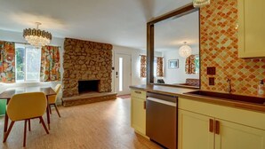 Een moderne keuken met een stenen openhaard, een eethoek met stoelen en een grote spiegel boven de gootsteen.