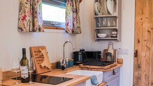 Una cocina con encimera de madera, un lavamanos, una botella de vino y una tabla de cortar.